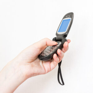 A vintage cellular flip phone being held in a Caucasian woman's hand