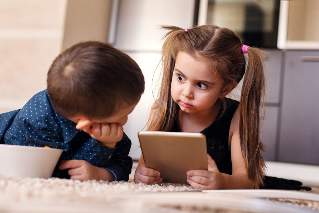 2 children of the gen alpha generations sharing a tablet